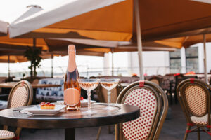 bottle of champagne, two glasses and delicious desserts on table in outdoor cafe