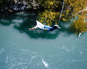 Man bungee jumping off bridge over river