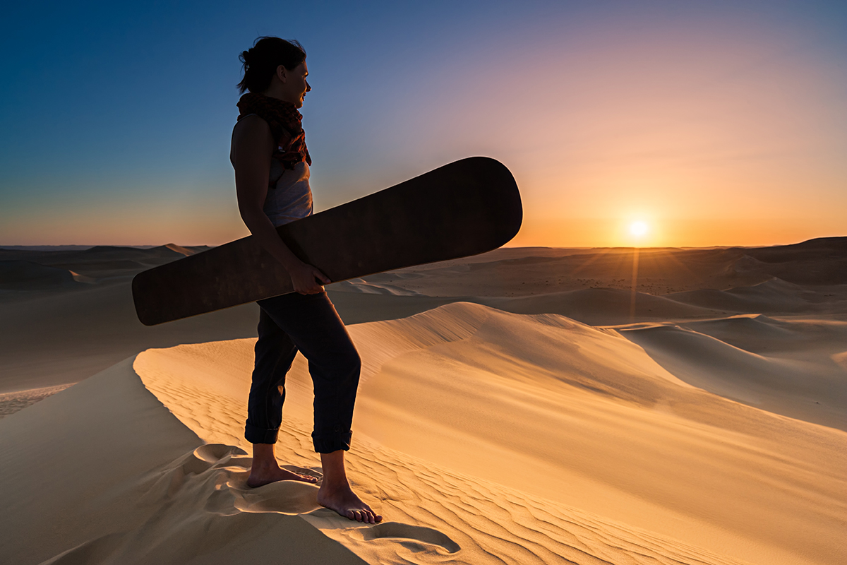 Young female sandboarding at sunset.