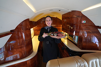 Cabin attendant serving charcuterie on part 135 charter flight