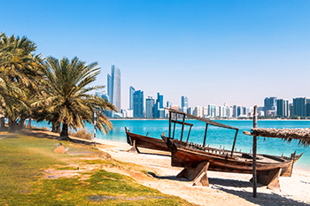 Beach with boats overlooking Abu Dhabi skyline