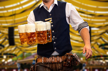 Man in traditional bavarian garments carrying steins at oktoberfest