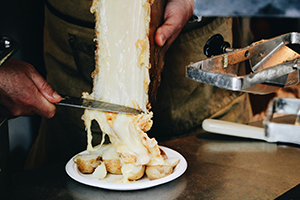 freshly melted raclette being served over potatoes