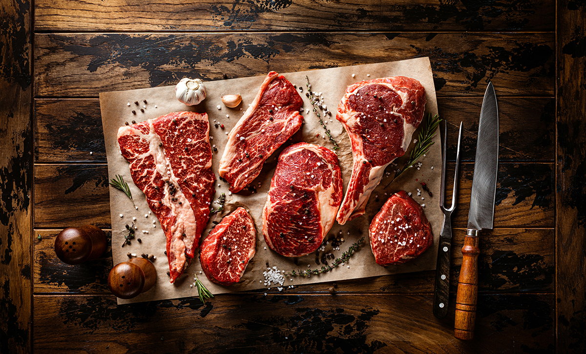 Assortment of aged steak cuts on chopping block in US Steakhouse