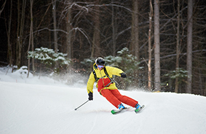 Young skier performing skiing trick. Ski training during snowfall. 