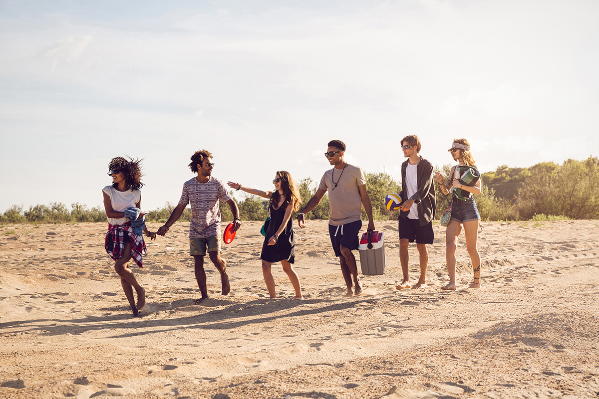 Diverse group of young friends having a walk on the beach at one of many spring break destinations